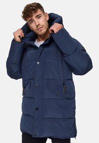 Doudoune bleue marine avec capuche, motif matelassé, boutons-pression, cordons de serrage réglables et poches latérales pour plus de commodité.