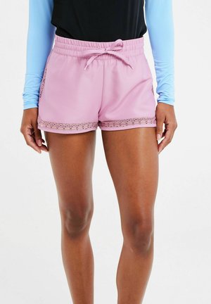 Shorts de sport roses avec une taille élastique et un cordon de serrage, ornés d'une bordure en dentelle sur l'ourlet. Fabriqués dans un tissu lisse et léger.