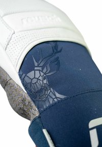 Sport Schuh mit oberem Teil aus weißem Leder, navyblauem Textil mit geometrischem Grafikdesign und strukturiertem grauen Sohle.