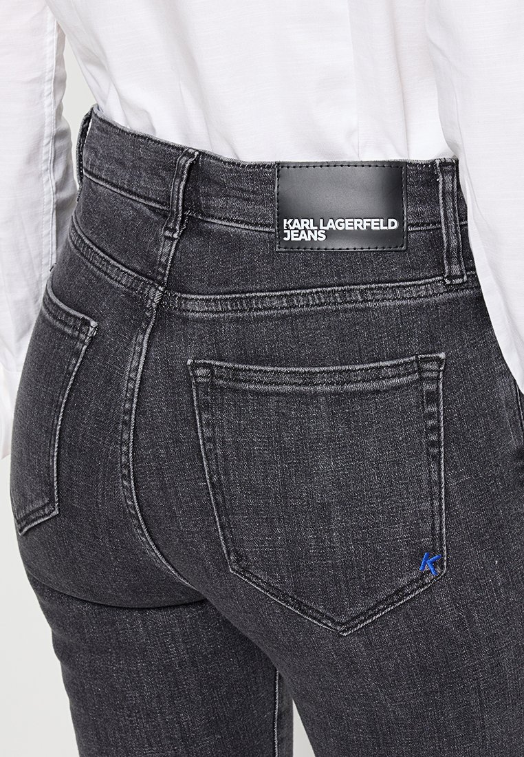 Jean en denim noir avec taille haute, dotés d'une étiquette en cuir et d'un petit accent bleu "K" sur la poche arrière. Design classique à cinq poches.