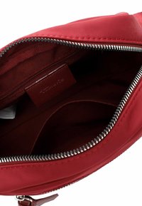 Red fabric bag with a smooth texture, zippered closure, and leather tag inside. Interior has a single compartment and minimal detailing.