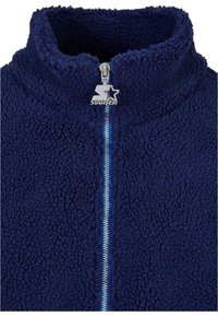 Navy blue fleece zip-up jacket with a high collar, featuring a silver zipper with a star-shaped pull tab and textured fabric.