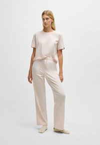 Ljusrosa loungematch med en figurvänlig kortärmad topp och vida byxor med elasticitet i midjan, båda gjorda av mjuk, slät tyg.