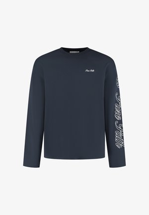 Marineblauw longsleeve t-shirt gemaakt van zachte stof. Heeft een ronde hals en een wit tekstontwerp op de linker borst en langs de rechter mouw.