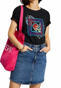 Sort kortærmet t-shirt med farverigt blomster- og geometrisk design; parret med en denimnederdel og en lys pink tote bag.