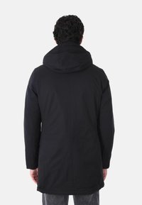 Cappotto isolante nero con cappuccio, caratterizzato da un design semplice, maniche lunghe e un taglio dritto, visto da dietro.