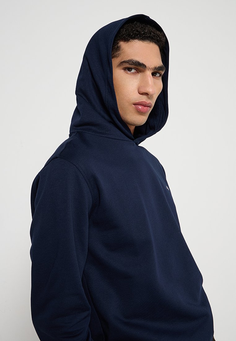 Marineblaue Kapuzenpullover mit einer vorderen Kängurutasche, strukturiertem Stoff und einer Kordelzugkapuze; mit Logo auf der Brust.