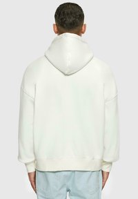 Hvid hætte sweatshirt med en stor, struktureret hætte og løs pasform. Fremstillet af blødt stof med ribbede manchetter og kant.