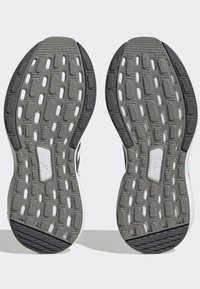 Suelas de zapatos de goma grises con ranuras texturizadas, acentos blancos y patrones moldeados para tracción. Diseño que no marca visible en el talón.