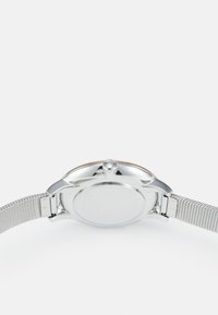 Reloj de metal plateado con correa de malla y caja redonda pulida. Incluye una corona en el lateral y una esfera de reloj lisa y sin marcas.