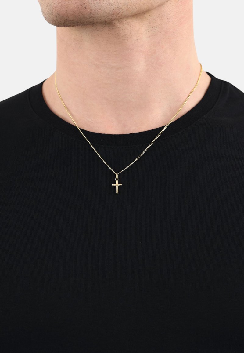 Collana in oro con un piccolo pendente a croce, indossata sopra una maglietta nera. La catena è sottile e texturizzata, in abbinamento allo stile del pendente.