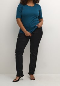 Tear ribbet kortærmet top parret med sorte slim-fit bukser og sorte strappy hæle. Enkel design med rund halsudskæring og subtil tekstur.
