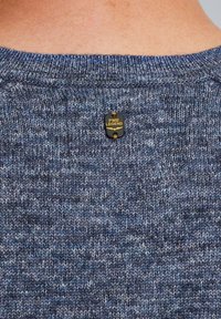 Blauer Strickpullover mit einem strukturierten Muster. Ein kleines schwarzes und goldenes "PME LEGEND"-Etikett ist am hinteren Halsausschnitt eingenäht.