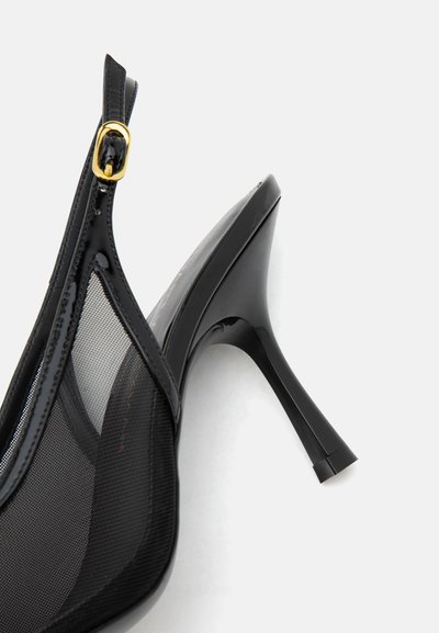 Escarpin slingback en cuir verni noir avec panneaux latéraux en mesh et boucle dorée sur fond gris.