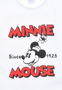 Camiseta blanca con un diseño gráfico que presenta "MINNIE MOUSE" en texto rojo en negrita e ilustración de Minnie Mouse en blanco y negro.