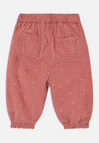 Sølvbukser i en myk rosa nyanse med en teksturert finish, med små hjerte mønstre og elastisk midje og mansjetter. To baklommer.