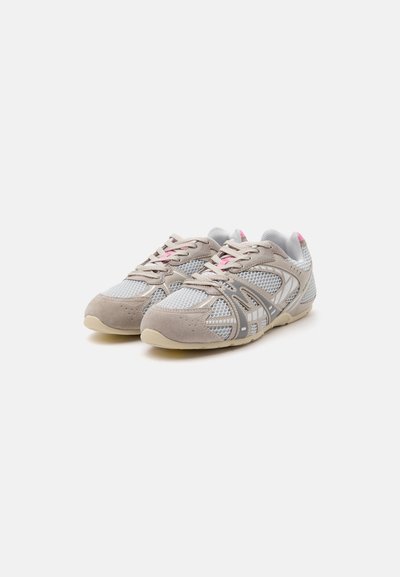 Paire de chaussures de sport grises et beiges avec panneaux en mesh blanc, empiècements en suédine beige, touches de rose et laçage sur fond blanc.