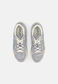 Szare buty sportowe z siateczkowym i zamszowym wierzchem, białymi sznurowadłami, wkładką amortyzującą oraz subtelnym wzornictwem z akcentami logo.
