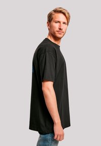 Zwarte katoenen T-shirt met korte mouwen, relaxte pasvorm, met een ronde halslijn en kleurrijke grafische accenten op de achterkant en zijkant.