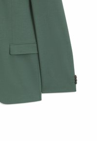 Manche de blazer vert et panneau latéral avec poche à rabat et deux boutons foncés au poignet, présenté sur fond blanc.
