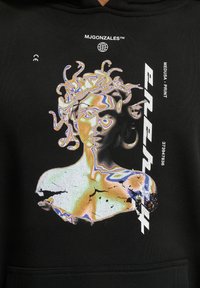 Felpa nera con un motivo grafico di una figura di Medusa distorta con accenti multicolore. Il materiale sembra avere una texture con un design a pullover.
