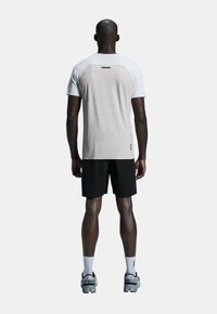 Ljusgrå och vit idrottströja med korta ärmar, i kombination med svarta shorts. Har en texturerad rygg och reflekterande detaljer. Sportskor fulländar looken.