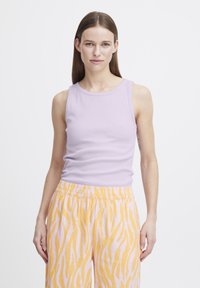 Top de culoare mov deschis, fără mâneci, din material cu nervuri, asociat cu pantaloni roz pastel cu un model de dungi galbene asemănătoare cu o tigra și o talie elastică.