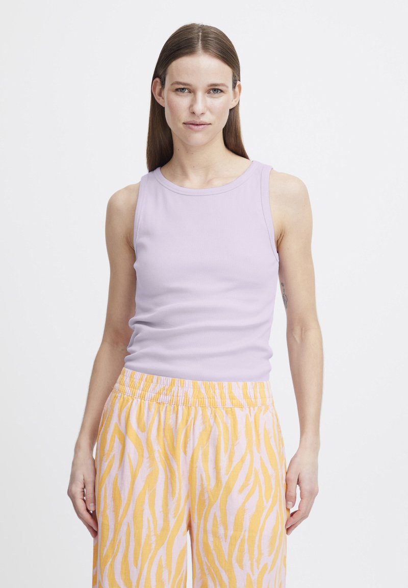 Top de culoare mov deschis, fără mâneci, din material cu nervuri, asociat cu pantaloni roz pastel cu un model de dungi galbene asemănătoare cu o tigra și o talie elastică.