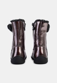 Botines metálicos marrones con un acabado suave, forro de puño de felpa, suela negra plana y detalle de correa lateral para mayor soporte.