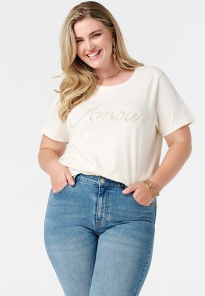 Crème kortemouwen t-shirt met "Amour" in parelaccenten. Gecombineerd met lichtblauwe high-waisted jeans, met voorzakken en een getailleerd silhouet.