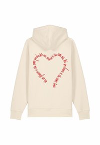 Haut à capuche couleur crème avec du texte rouge en forme de cœur au dos, en matière coton douce et au design décontracté.