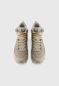 Une paire de bottes de randonnée hautes beige avec des lacets jaunes et des cols en mesh gris rembourrés, vues de dessus sur un fond blanc.