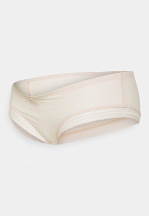 Beige damesondergoed met een gladde afwerking en een crossover ontwerp. Het heeft een zachte tailleband en een geschulpte rand langs de randen.