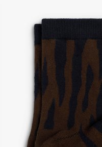 Calcetines marrones con un patrón de rayas de tigre azul oscuro. El tejido parece de punto, con un puño acanalado para un ajuste seguro.