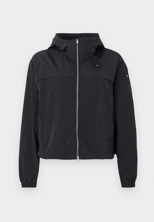 Veste à capuche légère noire avec fermeture éclair à l'avant, poignets élastiques et petits patchs logo sur la poitrine et la manche, présentée sur fond blanc.