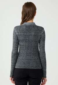 Gestrickter Ripp-Pullover in Grau und Schwarz mit einem hohen Kragen, schlanker Passform und langen Ärmeln. Verfügt über einen strukturierten Stoff und kontrastierende Farbmustern.