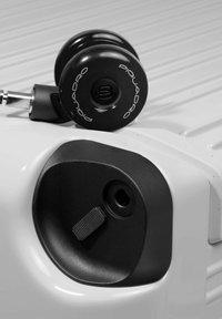 Black retractable handle and spinner wheel on a white suitcase, featuring a textured black accent and a circular logo, compact design.