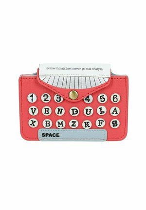 Portafoglio a forma di macchina da scrivere rossa con tasti rotondi neri e bianchi, barra spaziatrice blu e un foglio piegato con la scritta "Alcune cose non passano mai di moda."