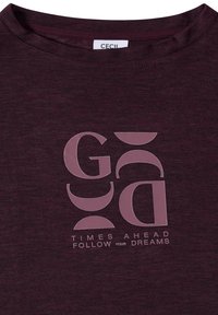 Chemise violette foncée avec des lettres abstraites violet clair et le texte « TIMES AHEAD FOLLOW YOUR DREAMS » sous le dessin.