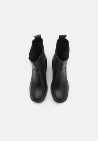 Černé kožené kotníkové boty s hladkým povrchem, kulatou špičkou a elastickými bočními panely. Mají poutko pro snadné obouvání.