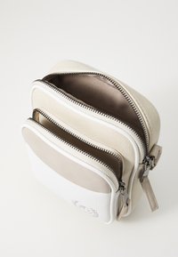 Borsa in pelle bicolore con tre scomparti con cerniera. Il colore principale è crema con un accento tortora. Presenta hardware in argento e dettagli testurizzati.
