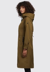 Parka impermeabile verde oliva con cappuccio, tasche laterali, chiusure con zip e cordini regolabili. Tessuto liscio con una vestibilità casual.