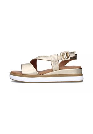 Sandal in metallo dorato con cinturini incrociati, chiusura con fibbia e tacco a cuneo, dotata di una suola bianca e una soletta in marrone per il comfort.