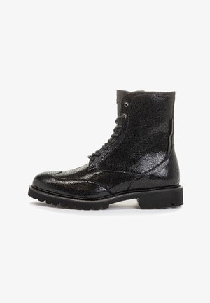 Botte noire en cuir texturé à brillance élevée avec lacets, semelle épaisse à crampons et design montant jusqu'à la cheville, vue latérale sur fond blanc.