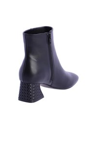 Bota de tobillo de cuero negro con un tacón block texturizado, cierre de cremallera lateral, punta afilada y un acabado suave.