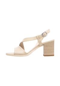 Sandalias de tacón de cuero beige con tiras cruzadas. Punta cuadrada, correa en el tobillo con hebilla y un tacón bloque texturizado.
