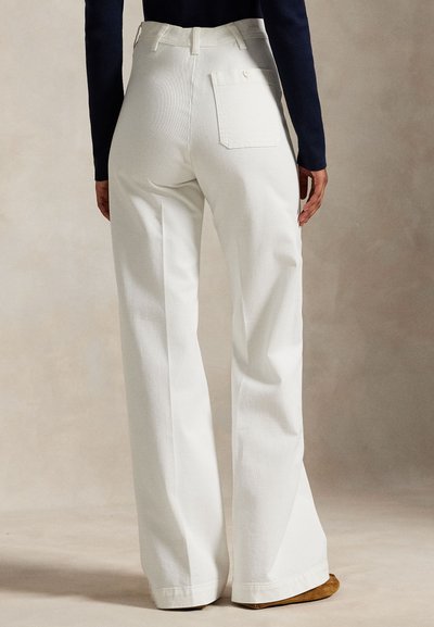 Hvite bukser med vide ben og høy midje, med en enkelt baklomme og et teksturert stoff. Buksekanten er svakt utsvingt.