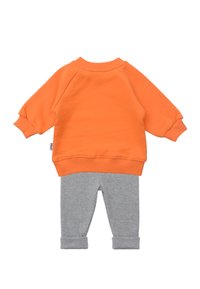 Oranges Sweatshirt mit Raglanärmeln und grauen Stretch-Hosen mit hochgerollten Säumen. Glatter Stoffeindruck; lässiges Design für Kleinkinder.