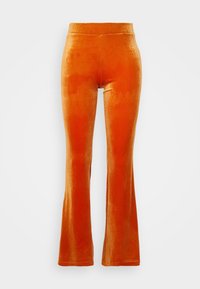 Pantalons évasés en velours orange vif, présentant une texture lisse, une taille élastique et une coupe ajustée au niveau des hanches.