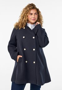 Navy double-breasted coat with gold buttons, featuring a relaxed fit and side pockets. Smooth fabric with a structured design.